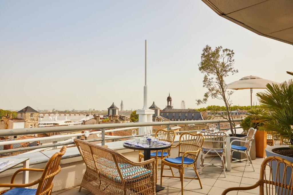 a patio with tables and chairs on a balcony at Hotel Indigo Bordeaux Centre Chartrons, an IHG Hotel in Bordeaux