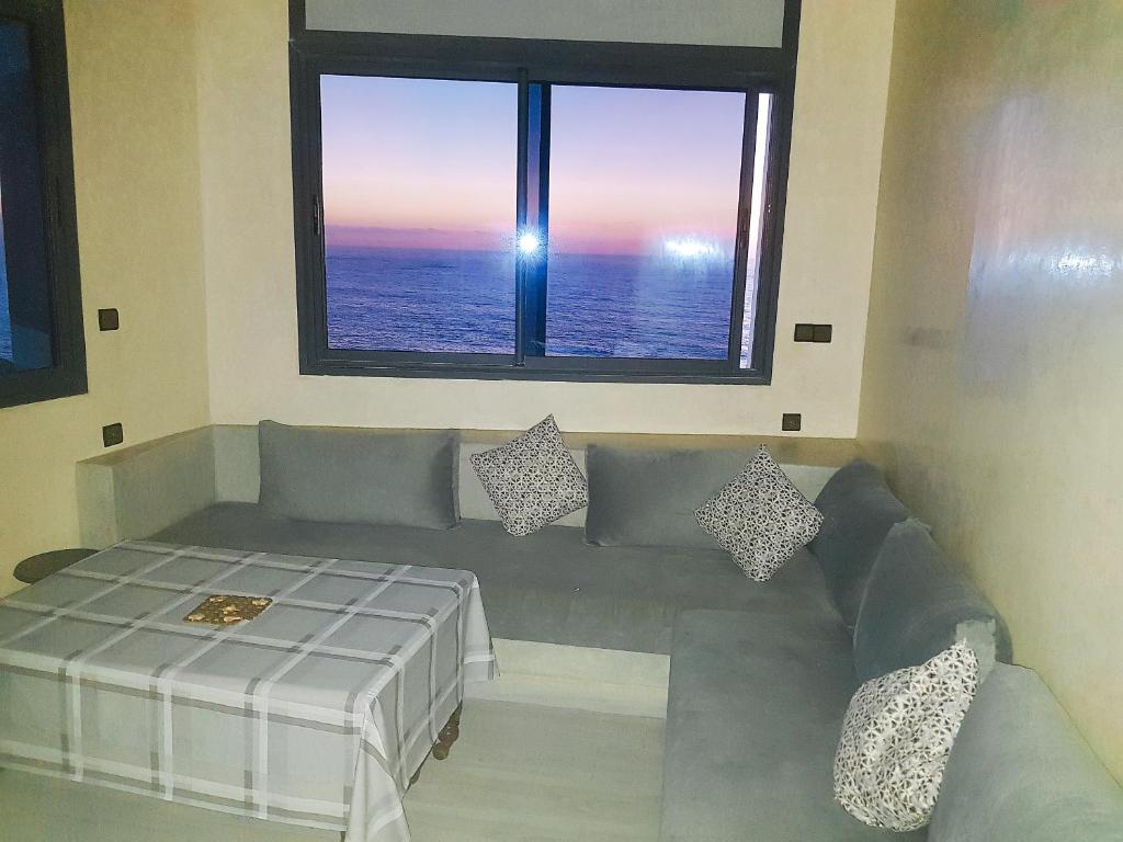 een woonkamer met een bank en een raam bij Amouage résidence in Sidi Ifni