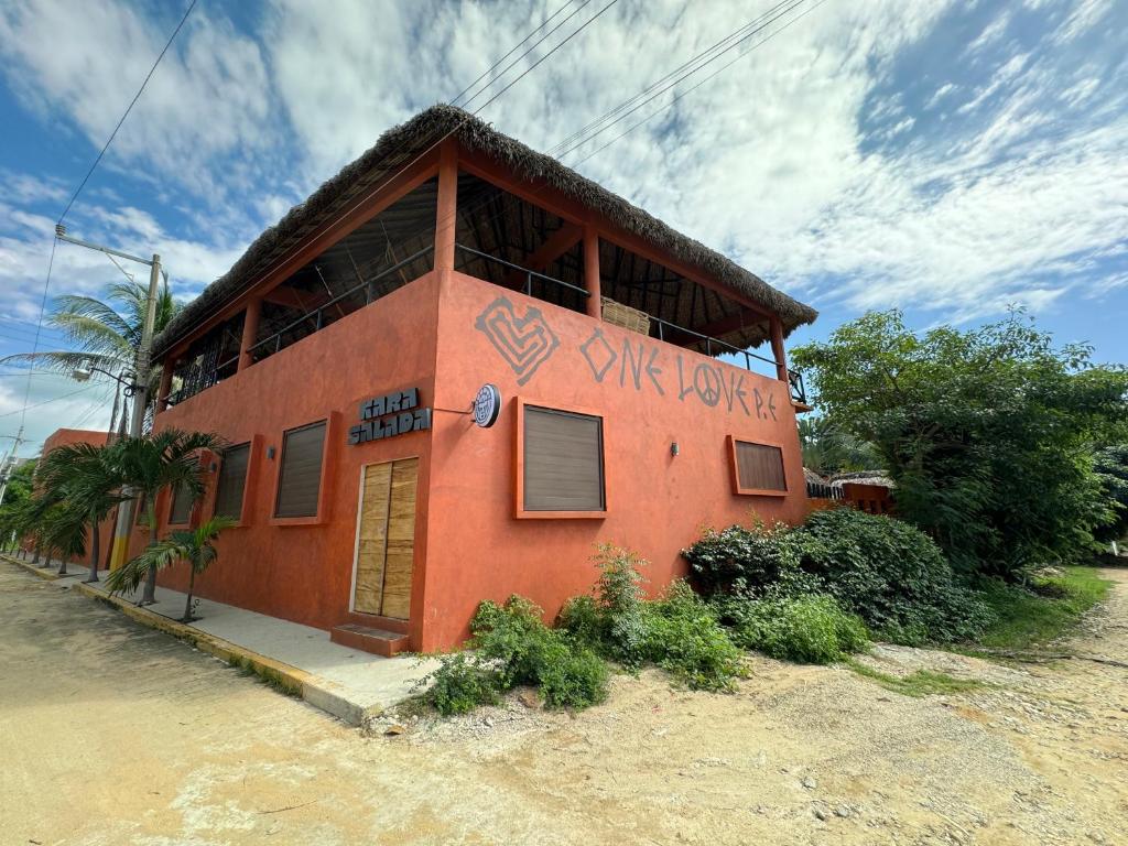 One Love Hostal Puerto Escondido في بويرتو إسكونديدو: مبنى احمر فيه كتابات على جانبه