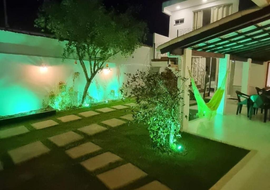 un jardín con luces verdes en una casa por la noche en Ressurgência loft, en Arraial do Cabo