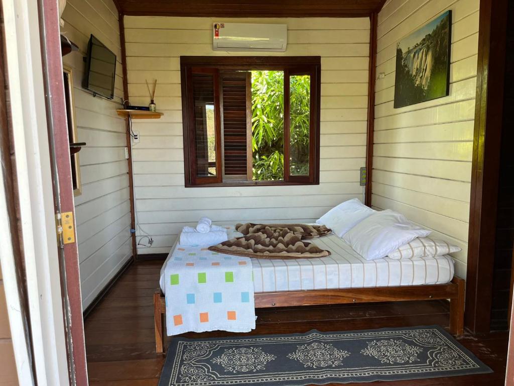 un petit lit dans une chambre avec une fenêtre dans l'établissement Pousada Arara Canindé, à Sao Jorge