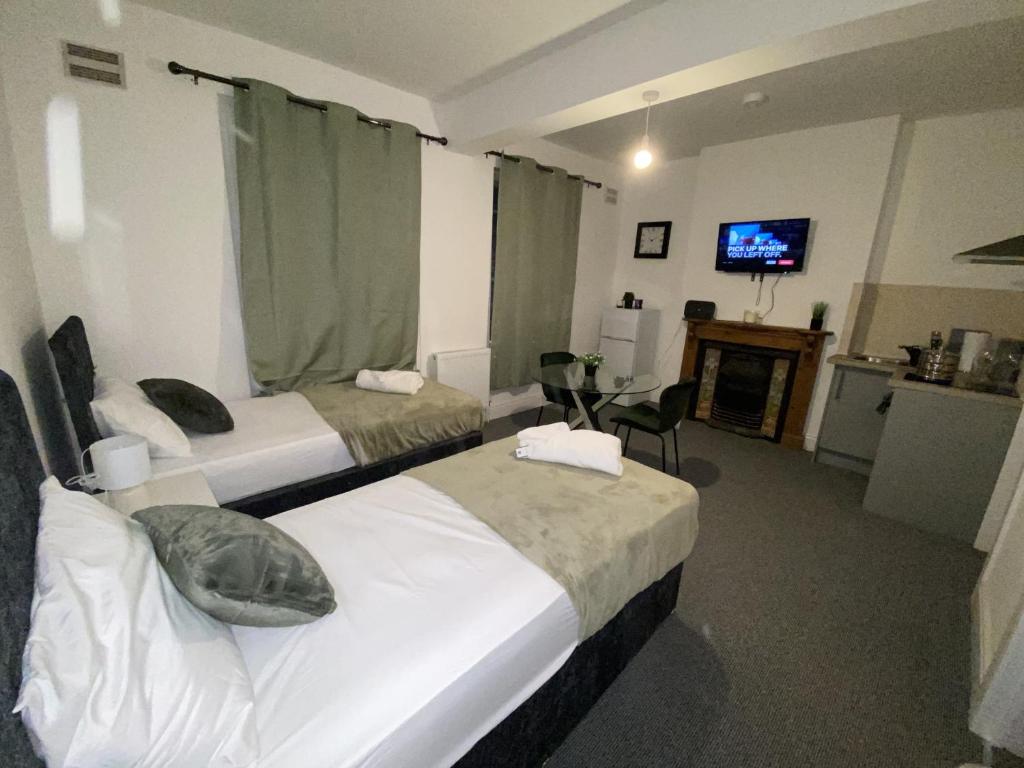 a hotel room with two beds and a television at Cosy 3BD Guesthouse w/ Private Bathrooms in Northampton