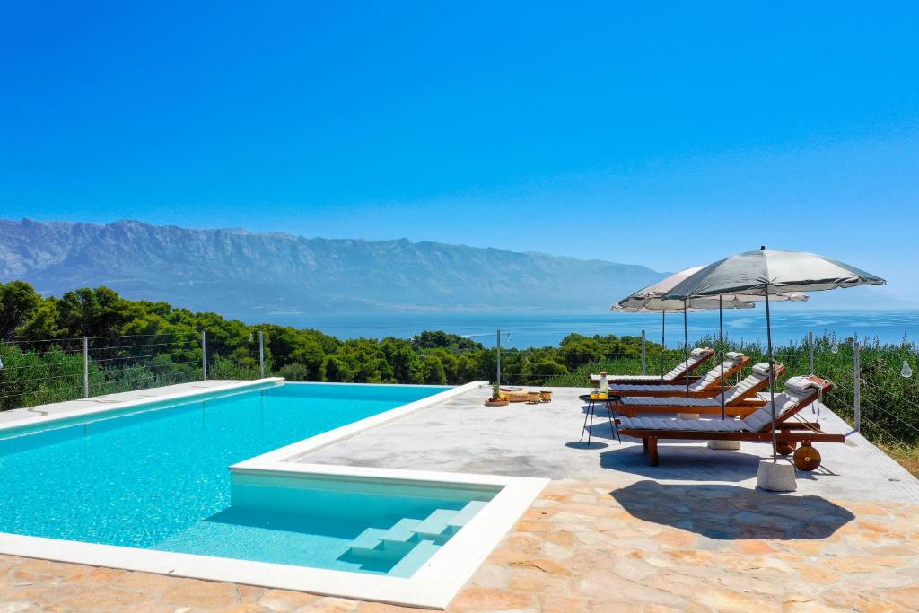 a swimming pool with lounge chairs and an umbrella at Villa Frida in Sumartin