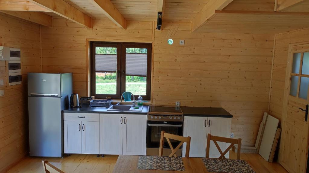 a kitchen with a refrigerator and a table in a cabin at Domki Dębowe Wzgórze in Potok Złoty