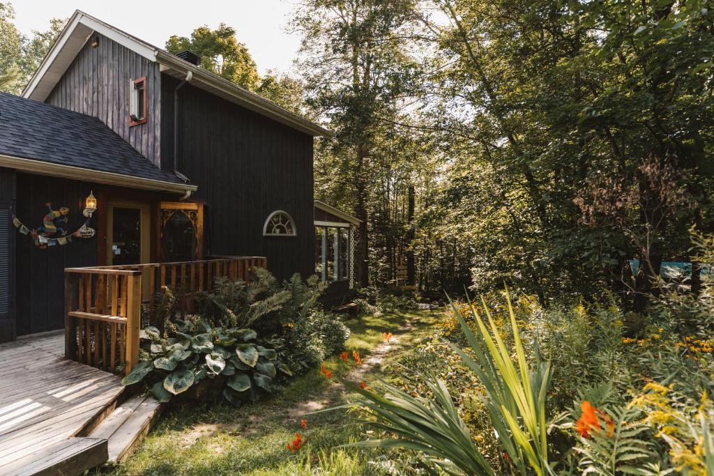 une maison noire avec une terrasse et un jardin dans l'établissement Auberge Yoga Salamandre, à Lac-Brome