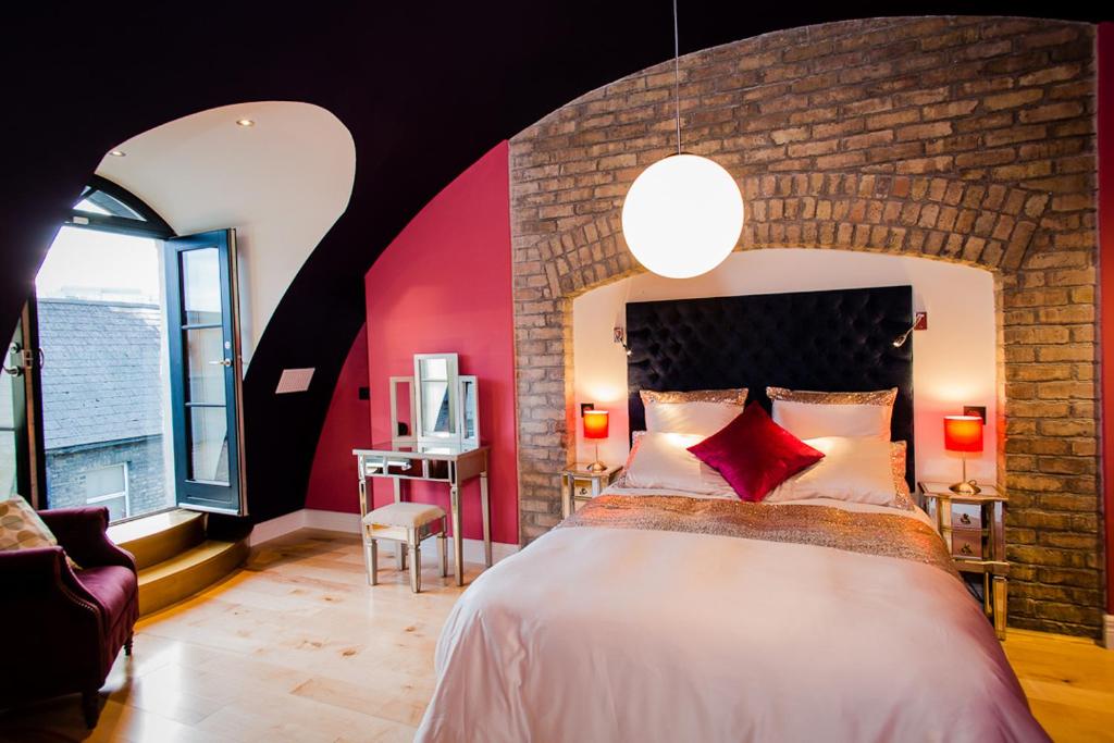 a bedroom with a large bed with a red wall at Luxury Townhouse in Dublin