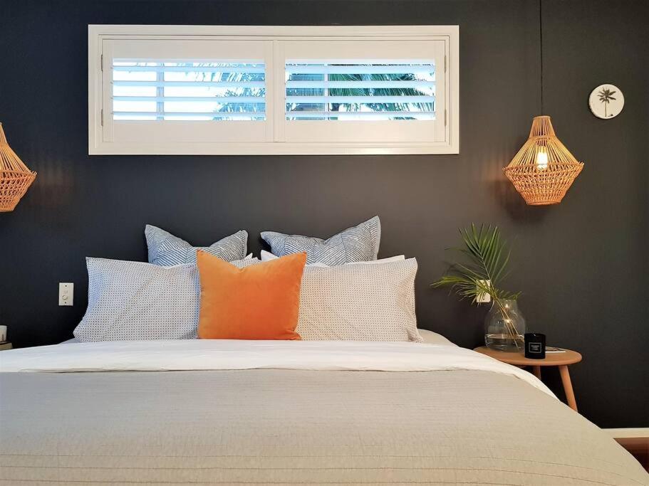 1 dormitorio con cama con almohadas y ventana en The Sunshine Shack - Boutique Holiday Home, en Sunshine Beach