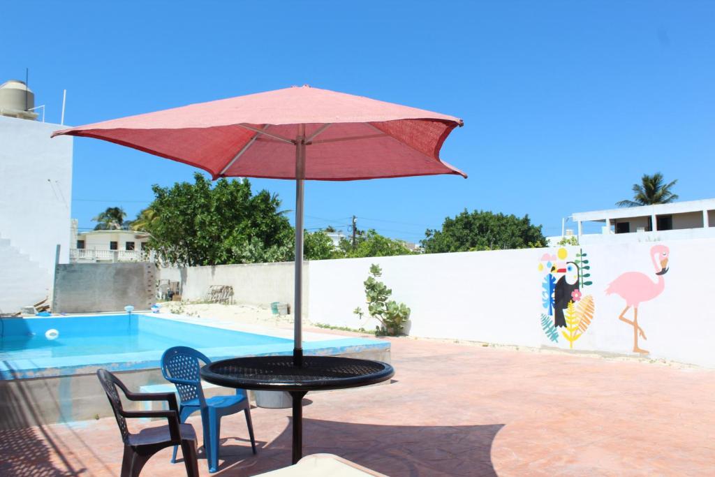 a table with an umbrella next to a pool at Casa Rojas, a una calle de la playa! in Progreso