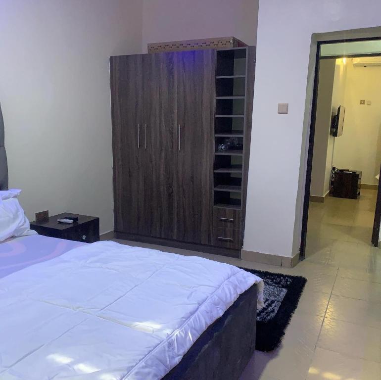 a bedroom with a bed and a wooden cabinet at Ace shortlet apartment in Abuja