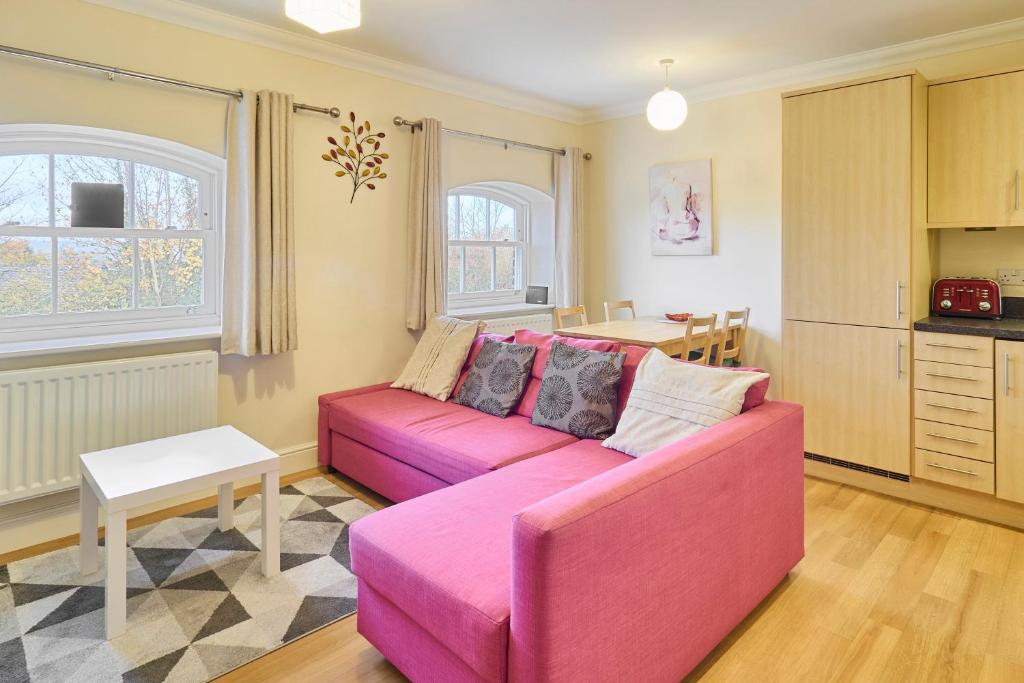 a living room with a pink couch and a table at Host & Stay - Nunnery Fields in Canterbury