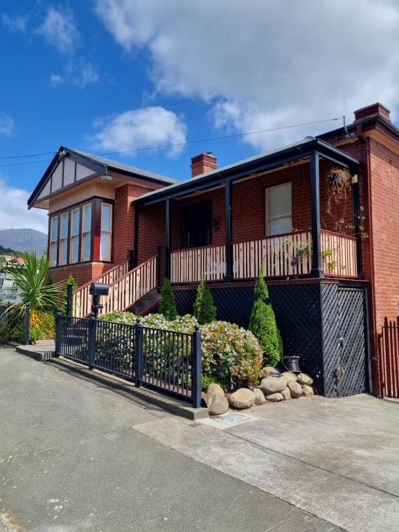 une maison en briques rouges avec une clôture noire dans l'établissement Lords Rest Apartment - Private and Central with Free Parking and Great WIFI, à Hobart