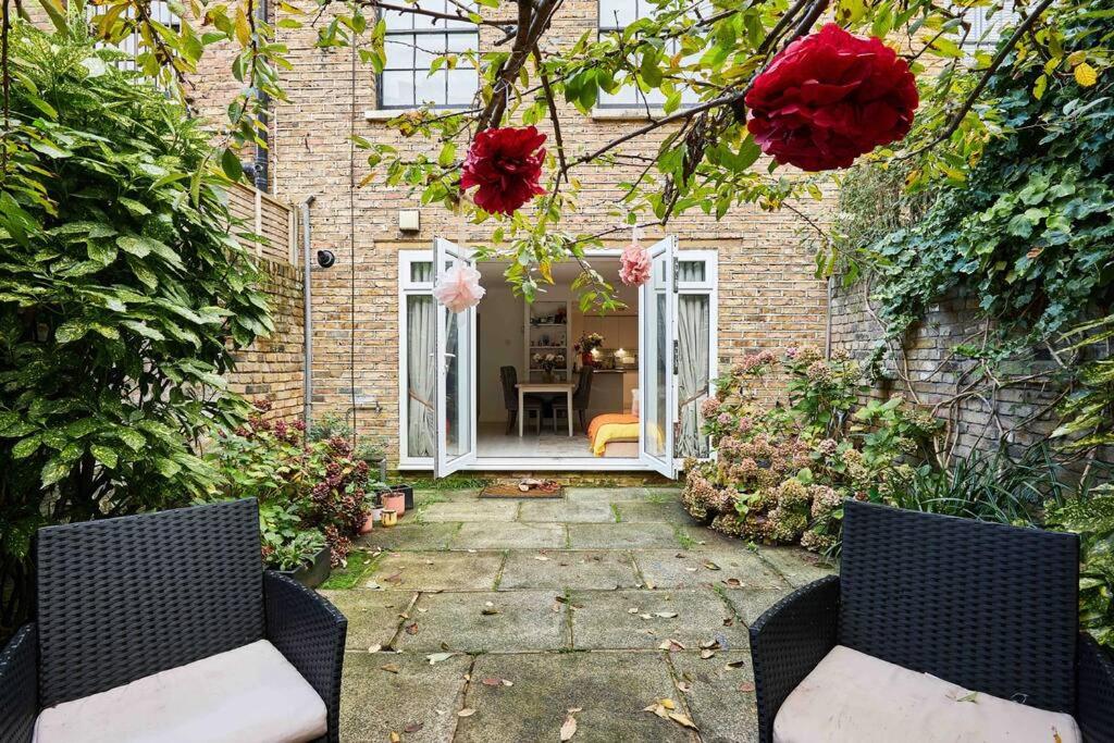 a patio with two chairs and a house with flowers at Little Venice Garden Apartment in London