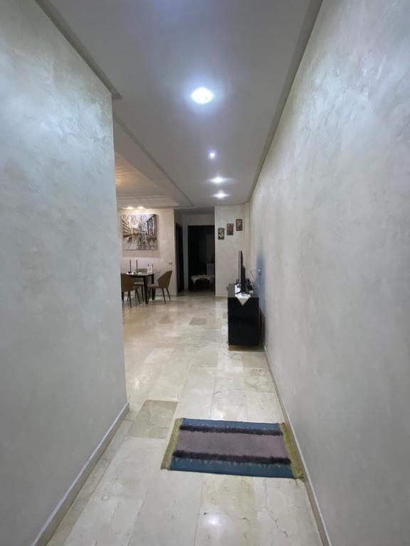a hallway with a white wall and a room with a table at Appartement de lux in Casablanca