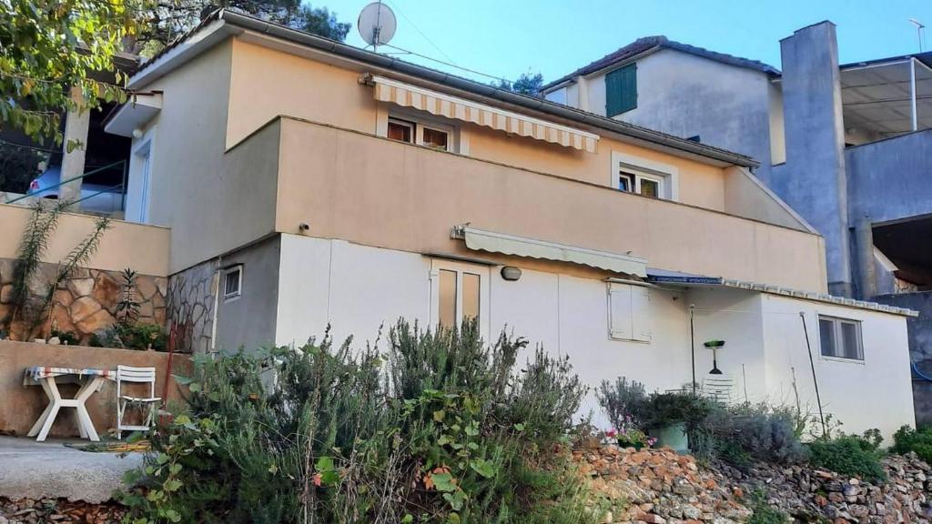 a large white house in front of a building at Apartments by the sea Basina, Hvar - 9673 in Vrbanj