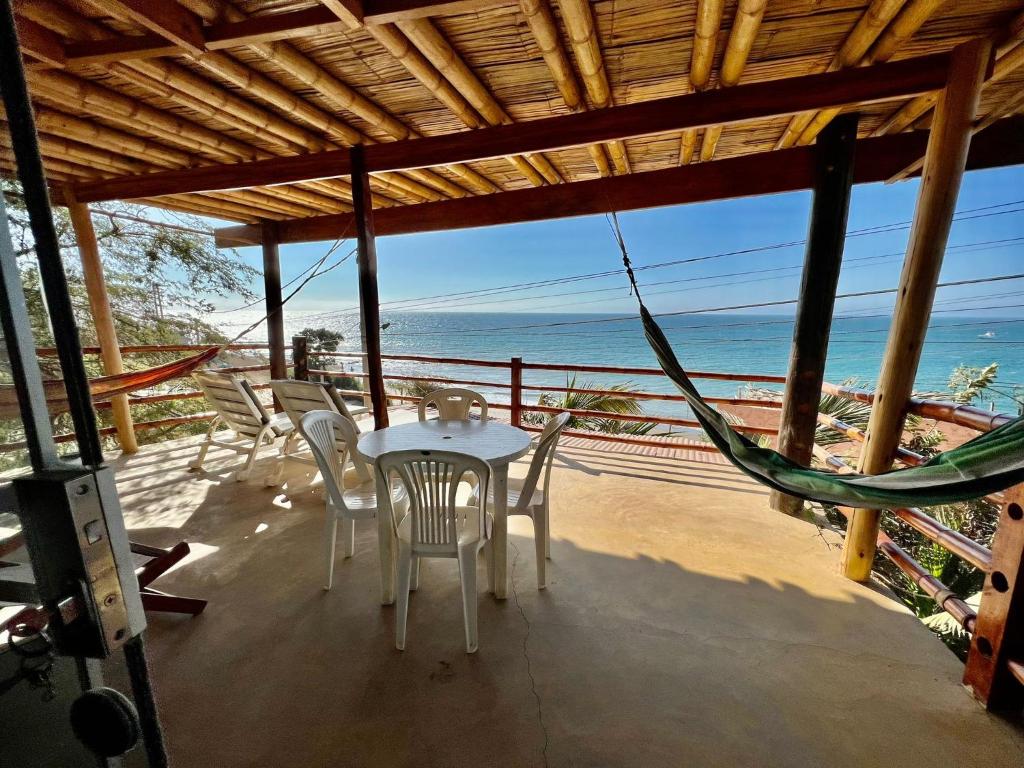 um alpendre com uma mesa e cadeiras na praia em Pocitas Casa Hotel - Playa & Piscina em Máncora