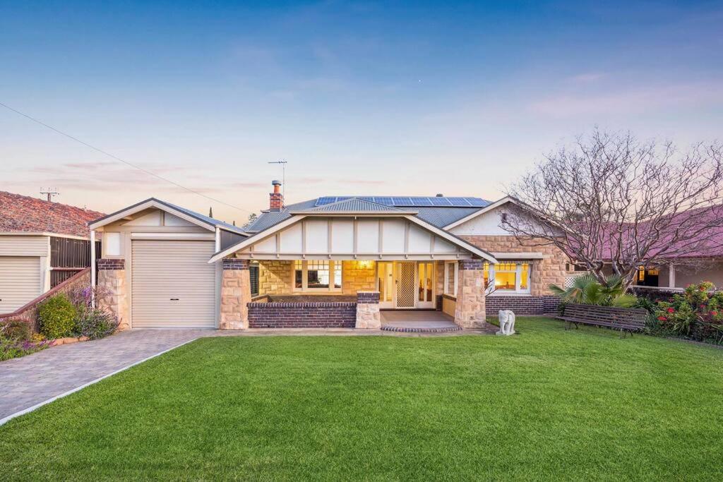 a brick house with a garage and a grass yard at Glenelg Beach Bungalow in Glenelg