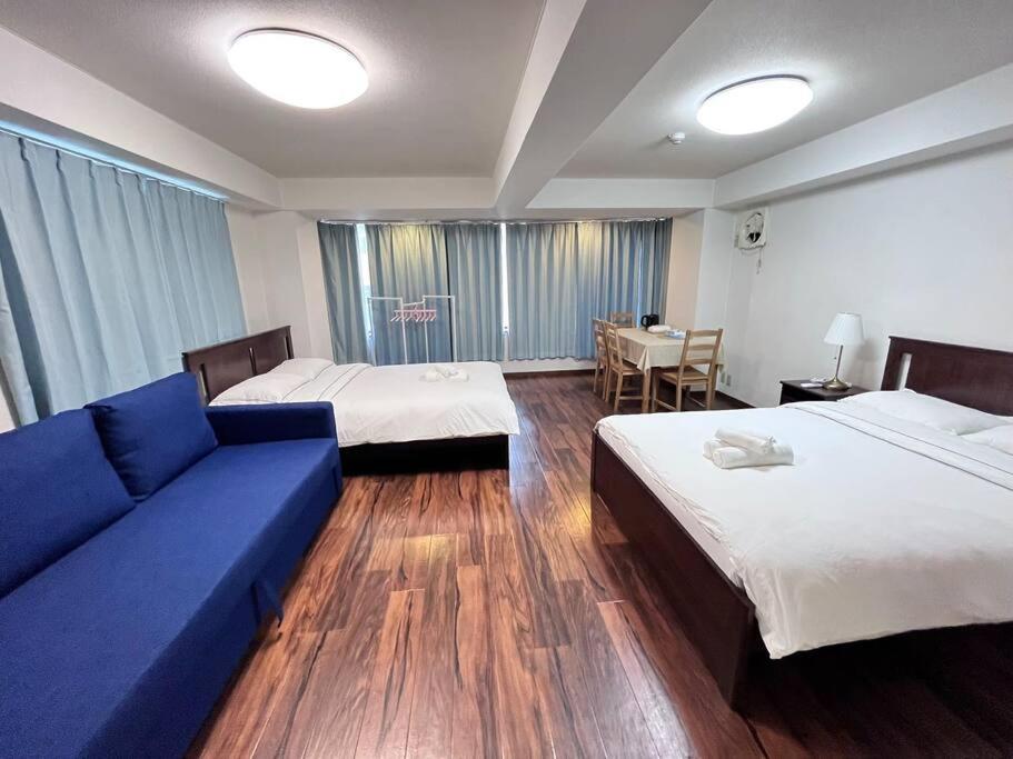 um quarto de hotel com duas camas e um sofá azul em 日本橋電気街　DenDenTown大面積40㎡工レベ-タ-直結5F em Osaka