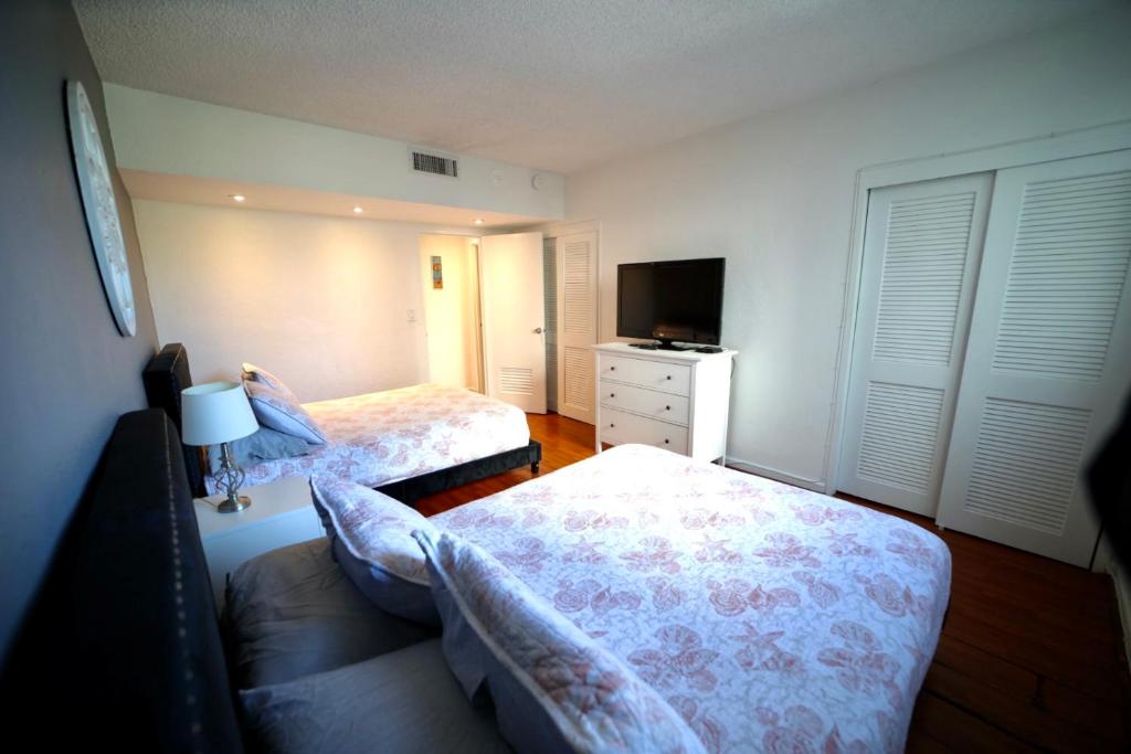 Habitación pequeña con 2 camas y TV. en Sunny Beachfront 2 Bdrm Condo in Hollywood FL, en Hollywood