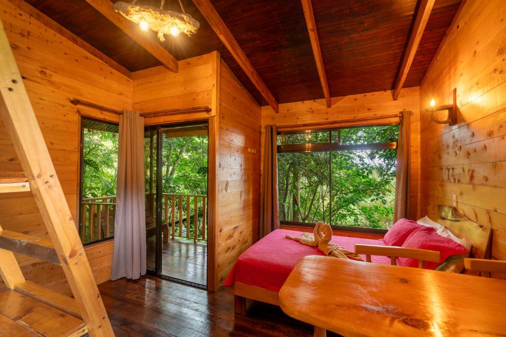 Cabaña de madera con cama y ventana en Cabaña La Montaña: Vistas increíbles y Mirador, en Turrialba