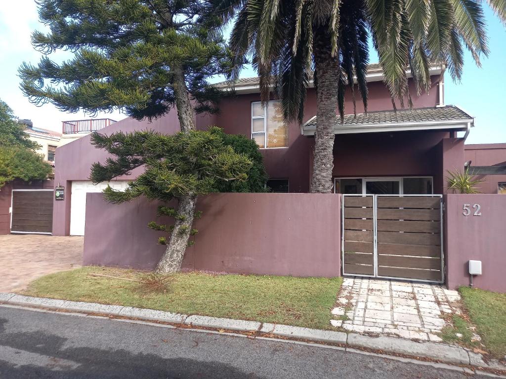 a pink house with a gate and a palm tree at PHAT Joe's Accommodation in Cape Town