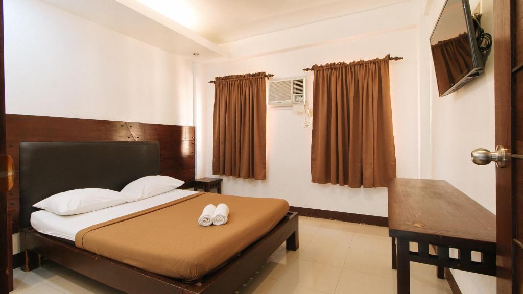 a bedroom with a bed with white pillows at WestCourt Inn Ilocos Sur in Bantaoay
