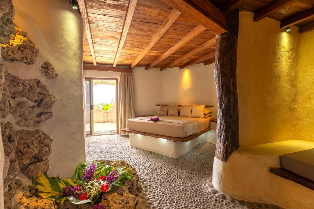 una camera con letto e parete in pietra di Rockwater Resort all’Isola di Tanna