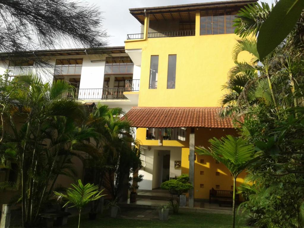 a yellow building with palm trees in front of it at Sanras Hotel and Restaurant in Galle