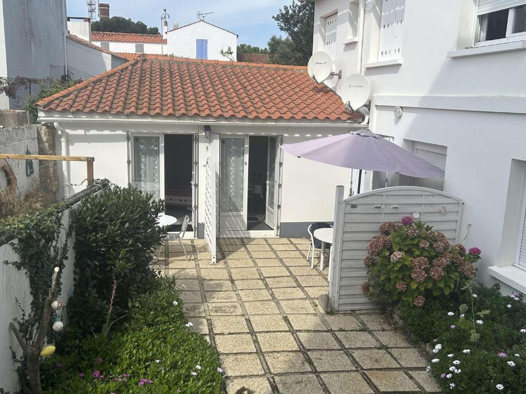 une maison blanche avec un parasol et une terrasse dans l'établissement Maison près du port, avec cour, terrasse équipée, à 400m de la plage - FR-1-224B-209, à Noirmoutier-en-l'lle