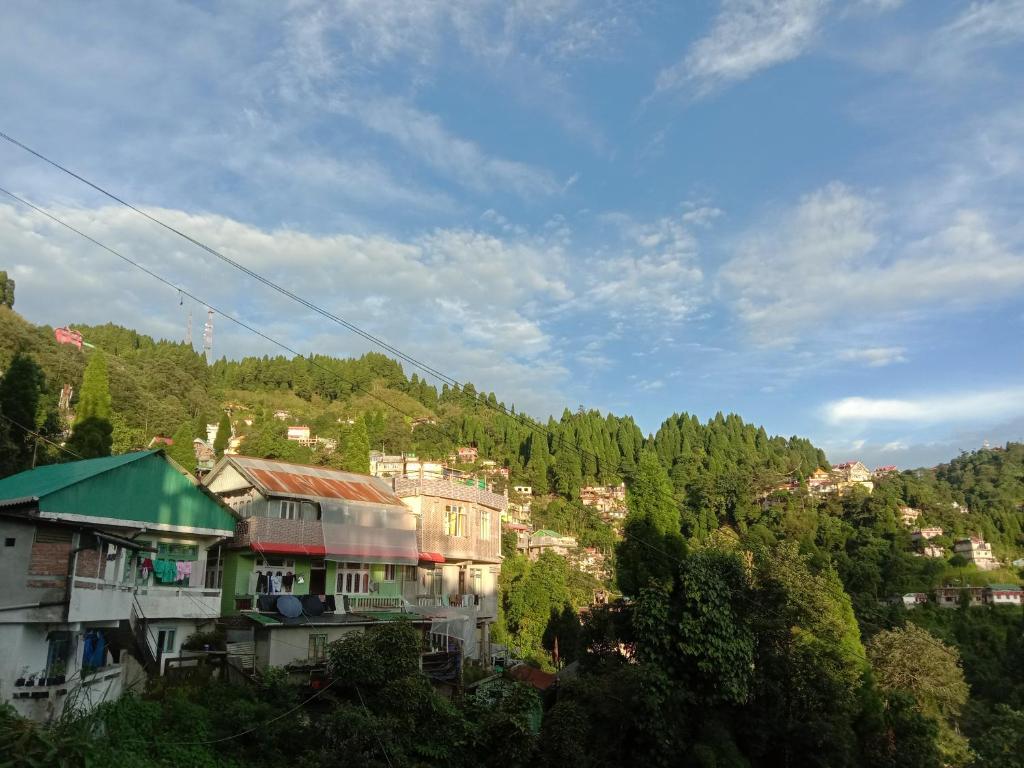 a group of buildings on a hill with trees at Goonkeshari Homestay in Ghum