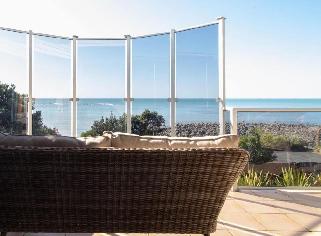 a wicker chair sitting in front of a large window at Beachfront Bliss On Wanaka Terrace Support Local in New Plymouth