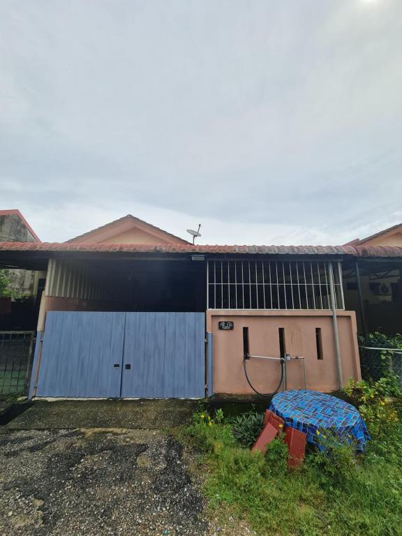 a house with a blue gate and a garage at Zara Homestay @ Kok Lanas in Ketereh