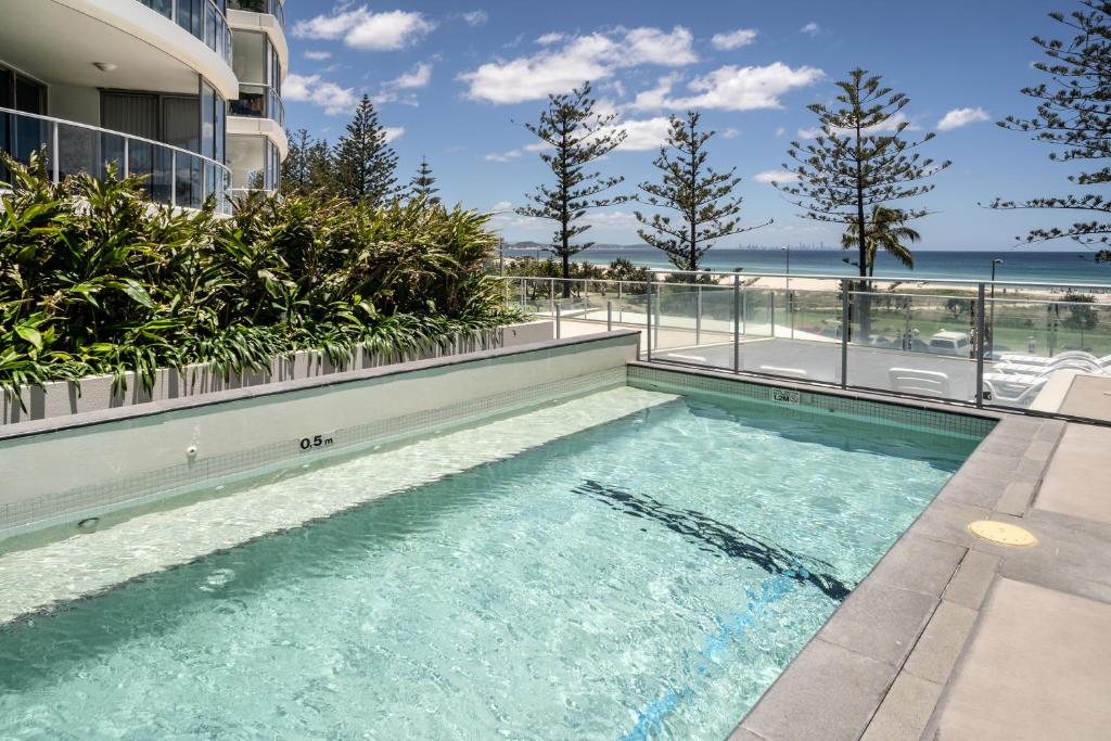 una piscina frente a un edificio con el océano en Reflections Tower Two, en Gold Coast