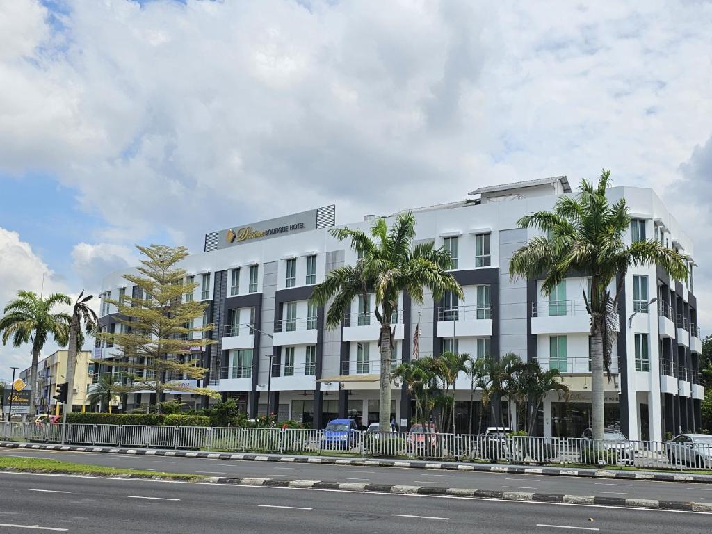 a white building with palm trees in front of a street at DeHome Boutique Hotel in Kuching