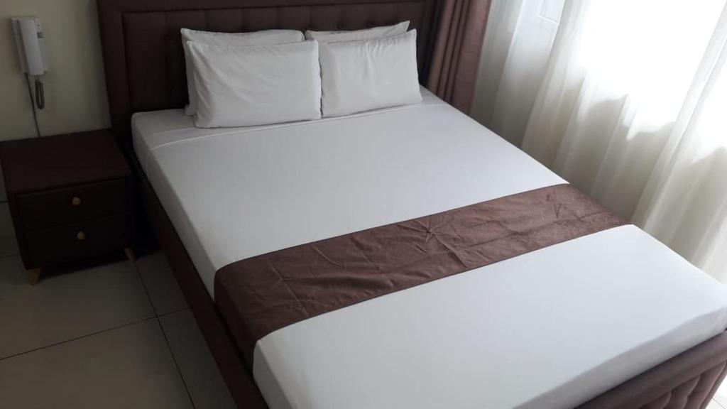 two beds in a hotel room with white sheets and pillows at Studio unit at The Breeze Residence in Manila