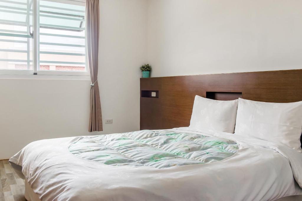 a white bed with a wooden headboard in a bedroom at 自由之丘民宿 l 寵物友善 in Taitung City