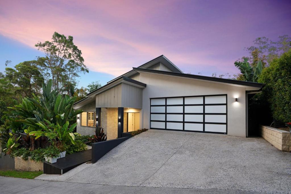 a house with a garage with a driveway at Cicada Close Hideaway in Buderim