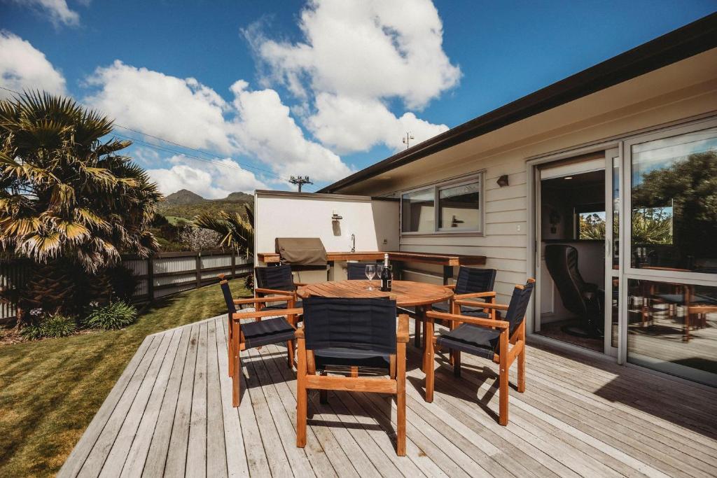una terrazza in legno con tavolo e sedie su una casa di Salt Life Oakura Beach a Oakura