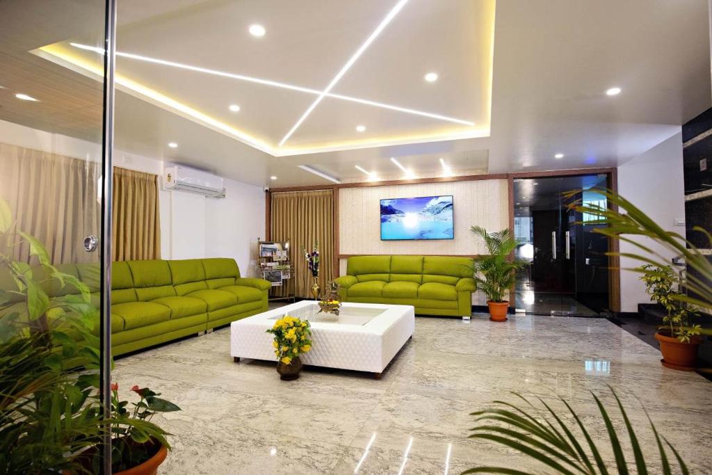 a living room with green couches and a white table at Hotel Grand Villa in Yelahanka