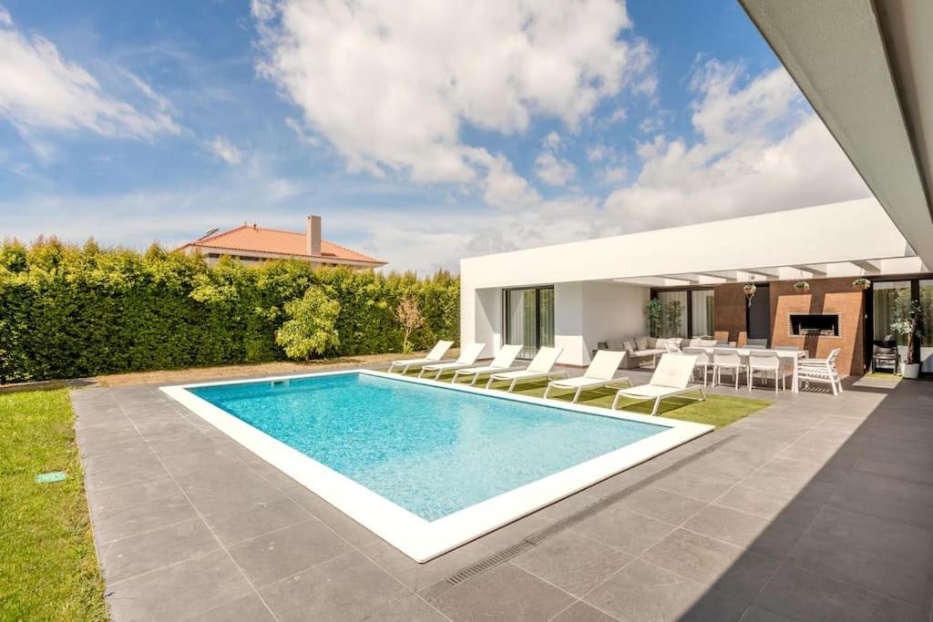 einen Pool mit weißen Stühlen und ein Haus in der Unterkunft Luxurious 5 bedrooms and with pool in Fernão Ferro