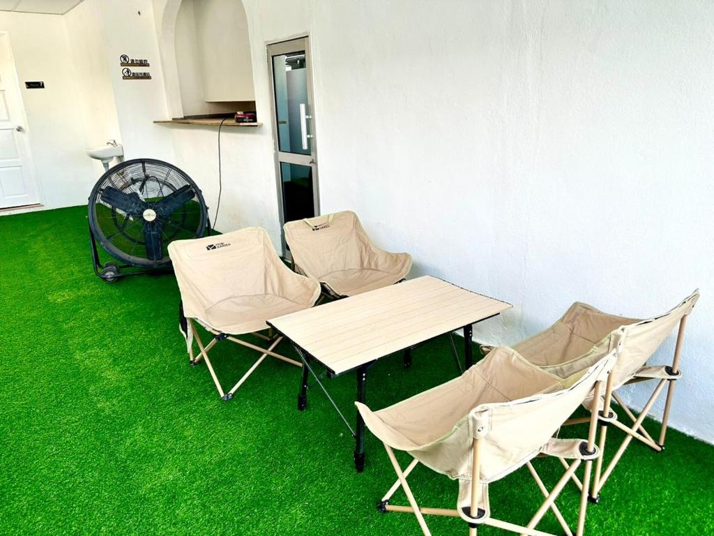 een tafel en stoelen met groen gras op de vloer bij Three Homestay in Perai