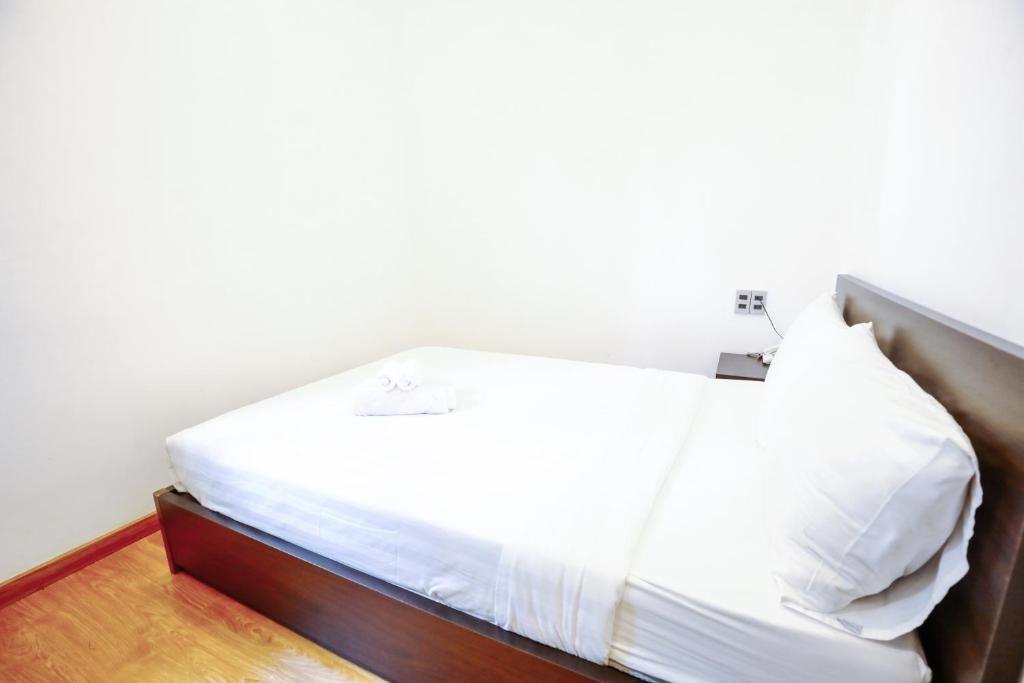 a bed with white sheets and pillows in a room at TTR Midtown View Hotel in Da Lat