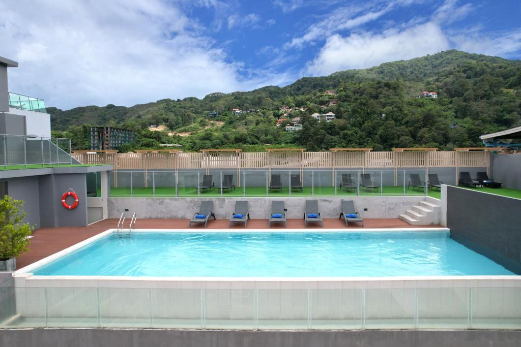 a swimming pool on top of a building with a mountain at Grace Patong Hotel in Patong Beach