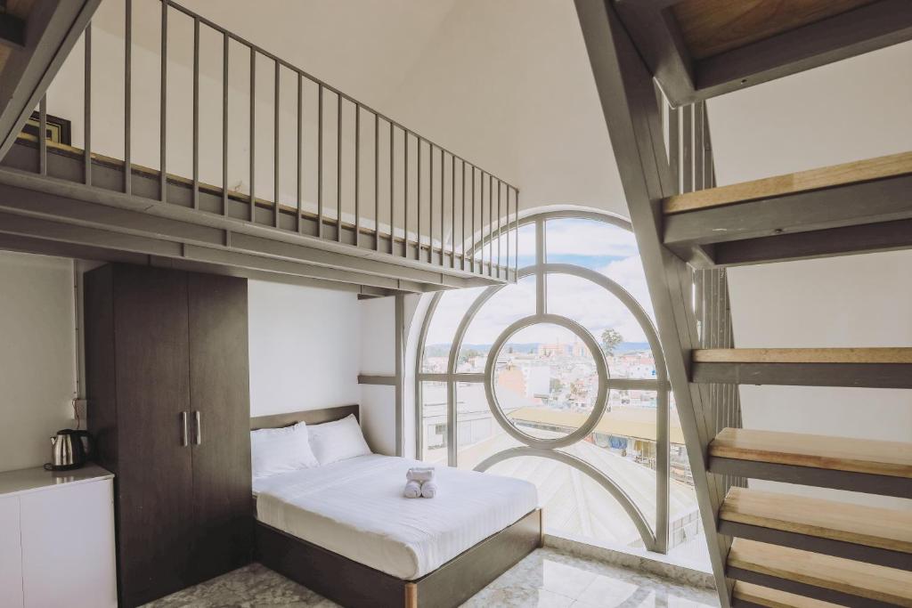 a bedroom with a bed and a spiral staircase at TTR Midtown View Hotel in Da Lat