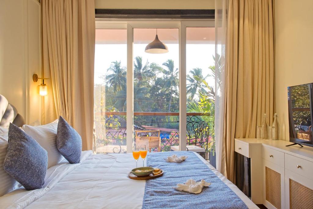 a bedroom with a bed with a view of a balcony at Mademoiselle Boutique Resort and Cafe in Vagator