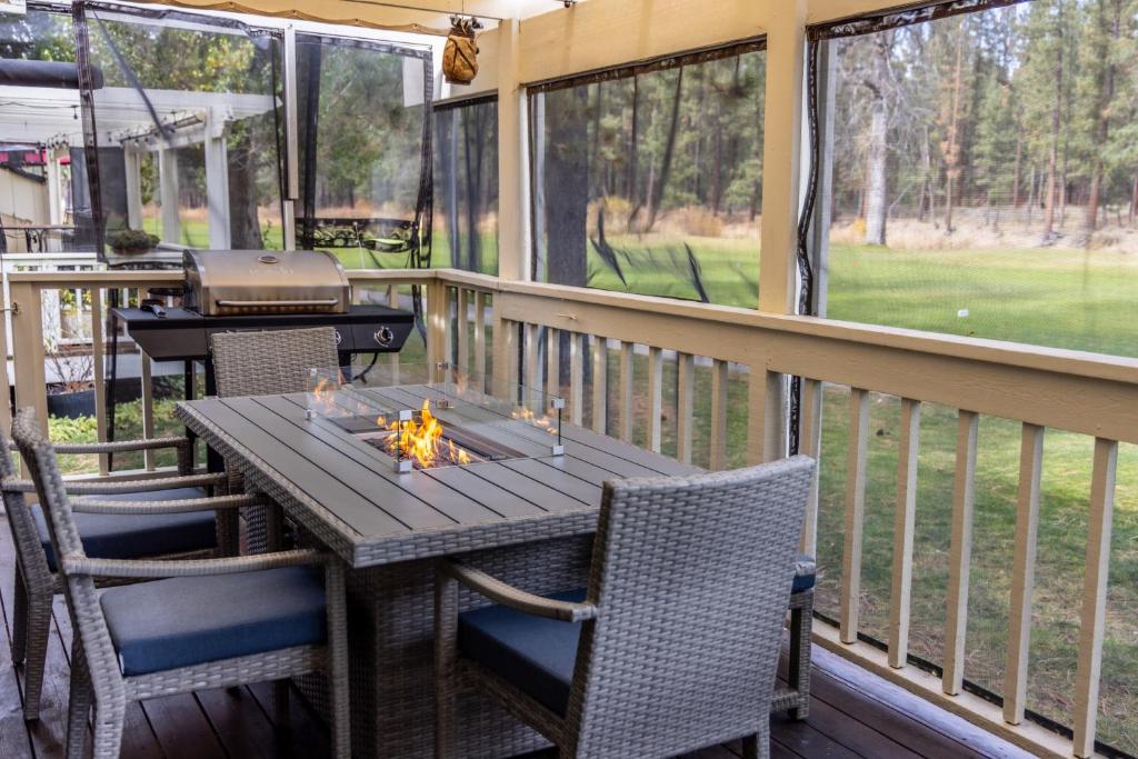 a screened porch with a table and chairs and a grill at Swing into Summer at our Mountain Home with a River View in Blairsden