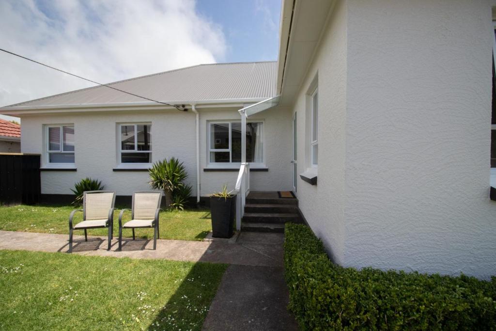 uma casa branca com duas cadeiras no quintal em Spacious In Strandon Great Value For A Family em New Plymouth