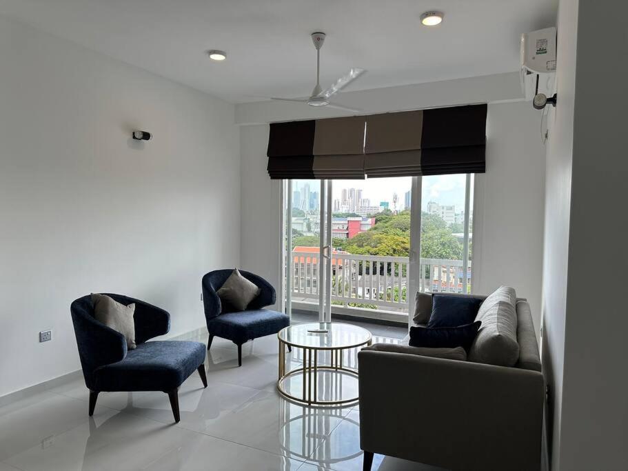 een woonkamer met 3 stoelen, een tafel en een raam bij Luxury 3 bed flat in Colombo 7 in Colombo