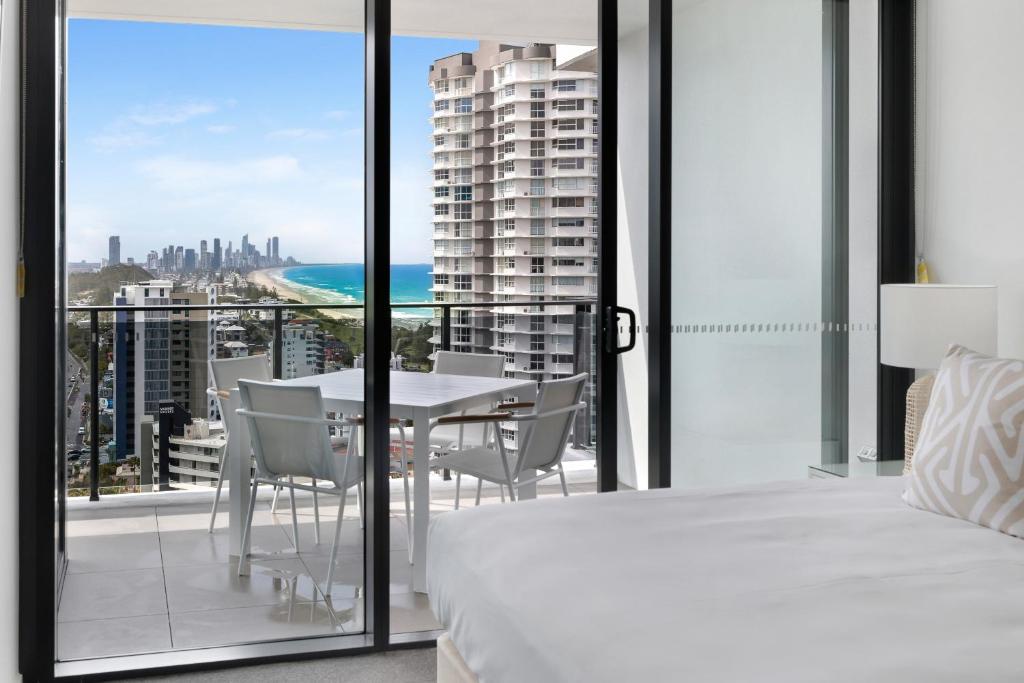 a bedroom with a bed and a balcony with a table and chairs at Sandbar Burleigh in Gold Coast