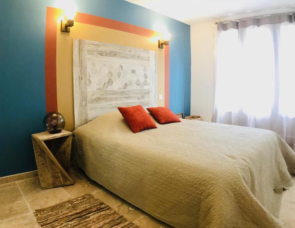1 dormitorio con 1 cama con 2 almohadas rojas en Appartements Cabiscol en Beaucaire