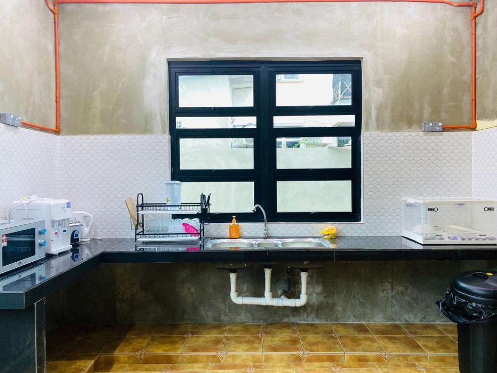 uma cozinha com um lavatório e uma janela em TERATAK ZAINAB GUEST HOUSE KOTA BHARU em Kota Bharu